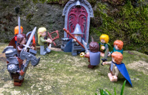 Die neun Gefährten der Ringgemeinschaft stehen vor einem Tor und beratschlagen sich