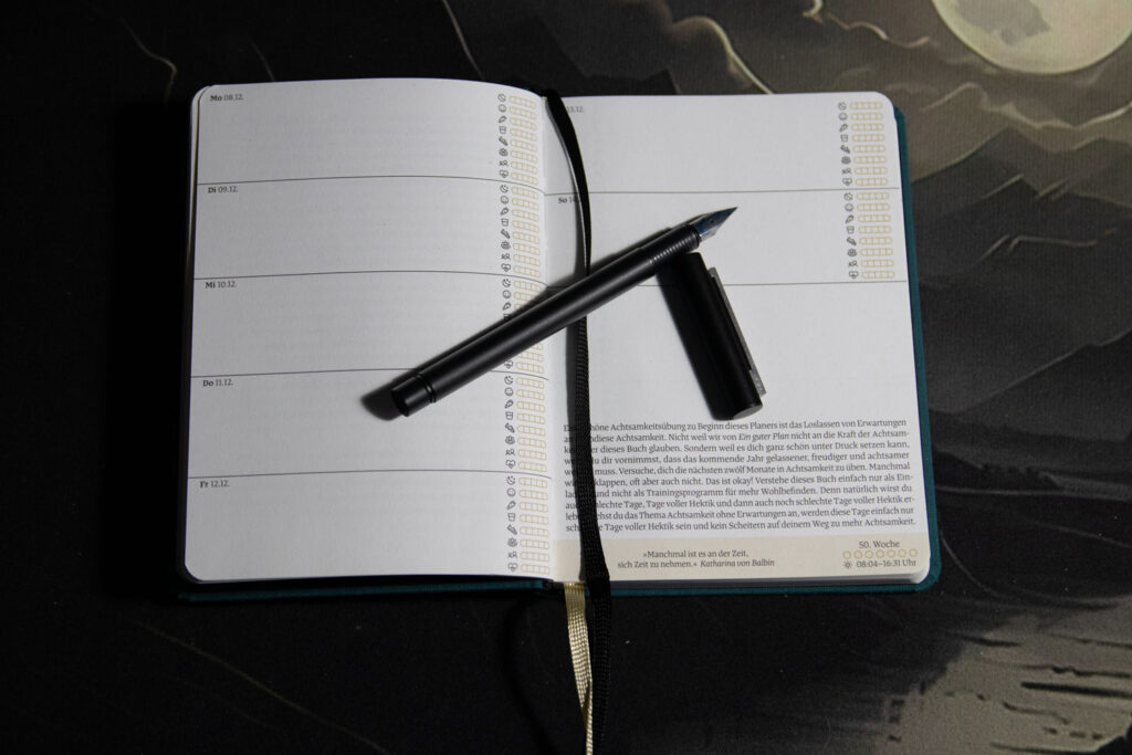 Terminplaner "Ein guter Plan Mini 2026" aufgeschlagen mit geöffnetem Füller